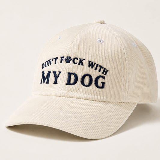 An off-white corduroy baseball cap with the embroidered text 'DON'T F*CK WITH MY DOG' in navy blue, featuring a paw print icon inside the letter 'O'.