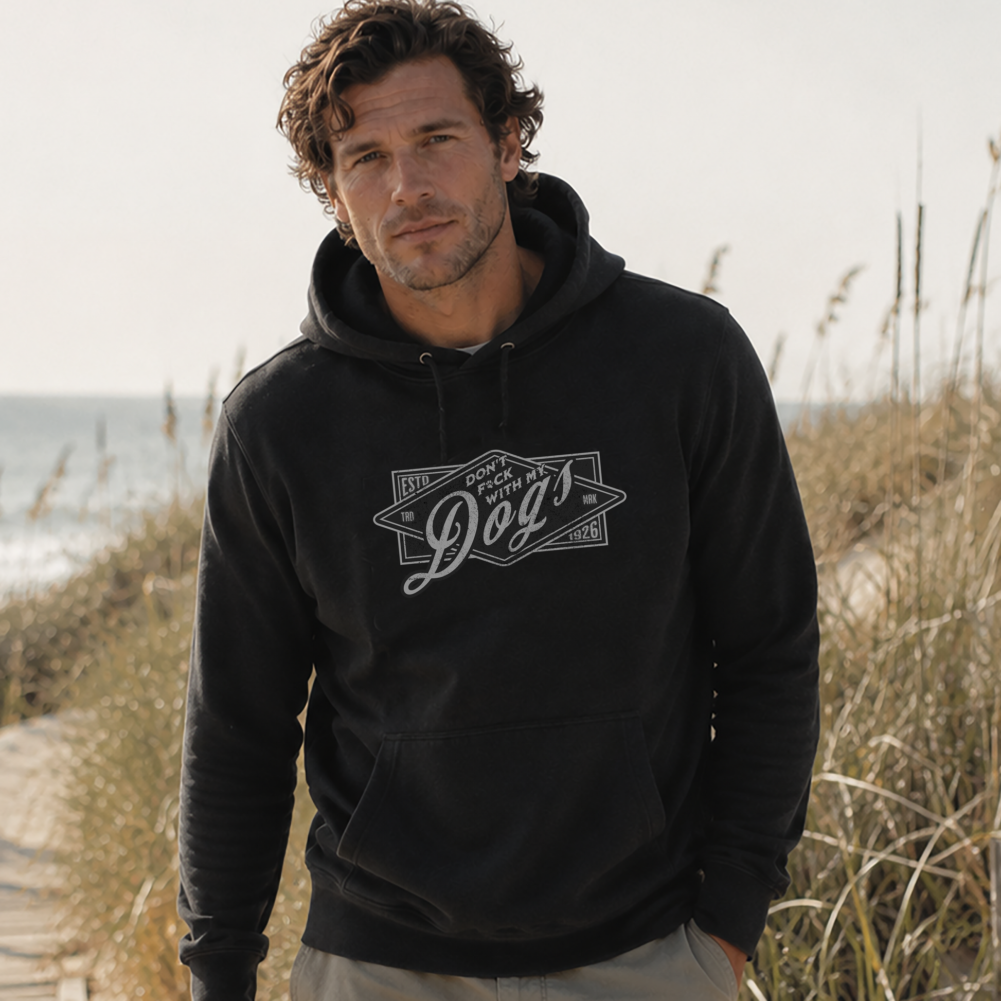 Man wearing a black hoodie with a logo on a beach
