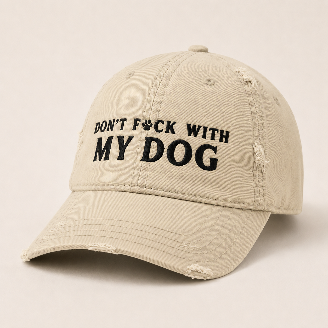 A distressed beige baseball cap with black embroidered text reading 'DON'T F*CK WITH MY DOG' on the front, shown against a plain light beige background.