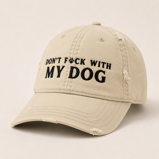 A distressed beige baseball cap with black embroidered text reading 'DON'T F*CK WITH MY DOG' on the front, shown against a plain light beige background.