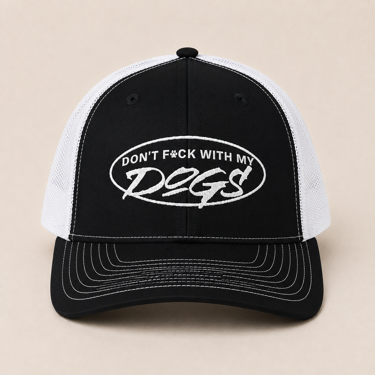 A black and white trucker hat with a black front panel and brim, white mesh back panels, and white embroidered text reading 'DON'T F*CK WITH MY DOGS' inside an oval on the front.
