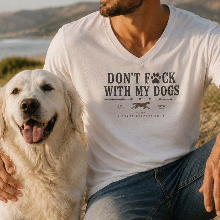Man wearing a white t-shirt with a dog-themed graphic and text, sitting next to a dog outdoors.