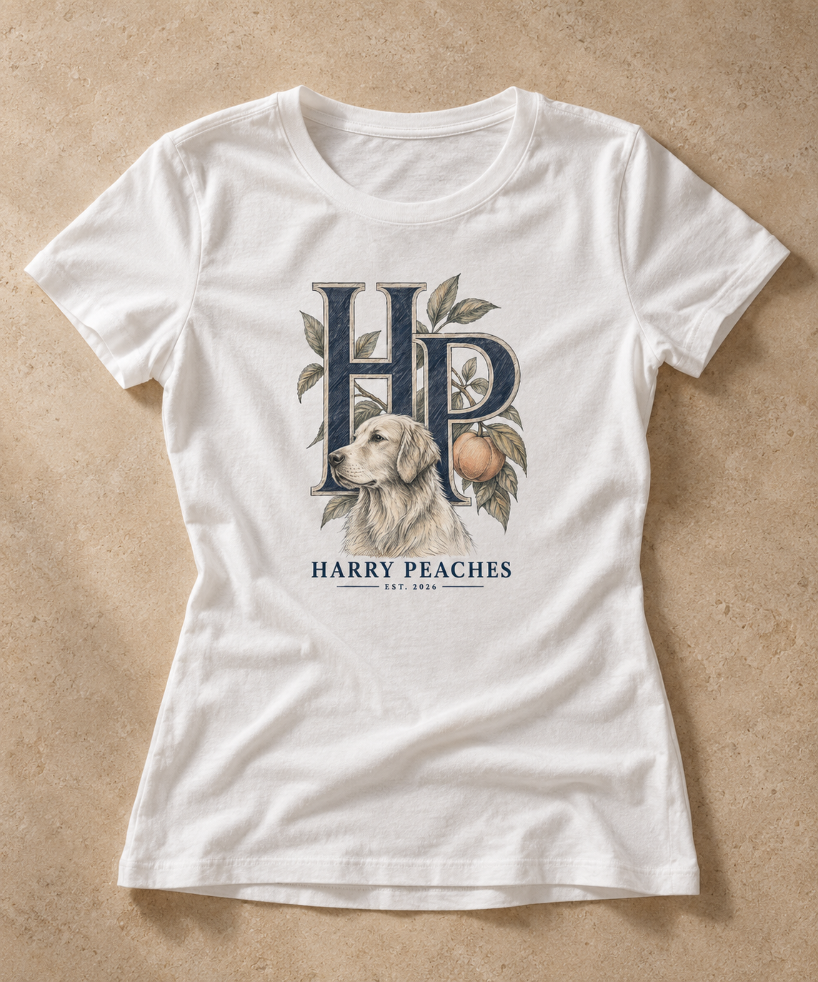 A white short-sleeve crewneck t-shirt laid flat on a textured beige background. The front of the shirt features a graphic print with the letters 'HP' in dark blue, a golden retriever dog, a peach, and the text 'HARRY PEACHES EST.