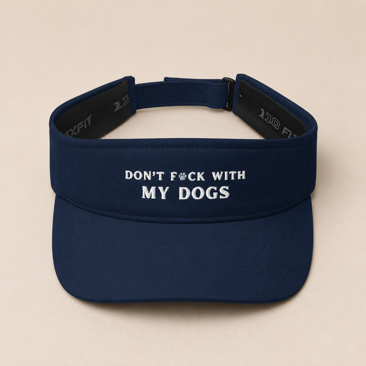 A navy blue athletic visor with white embroidered text reading 'DON'T F*CK WITH MY DOGS' on the front, shown against a solid beige background.