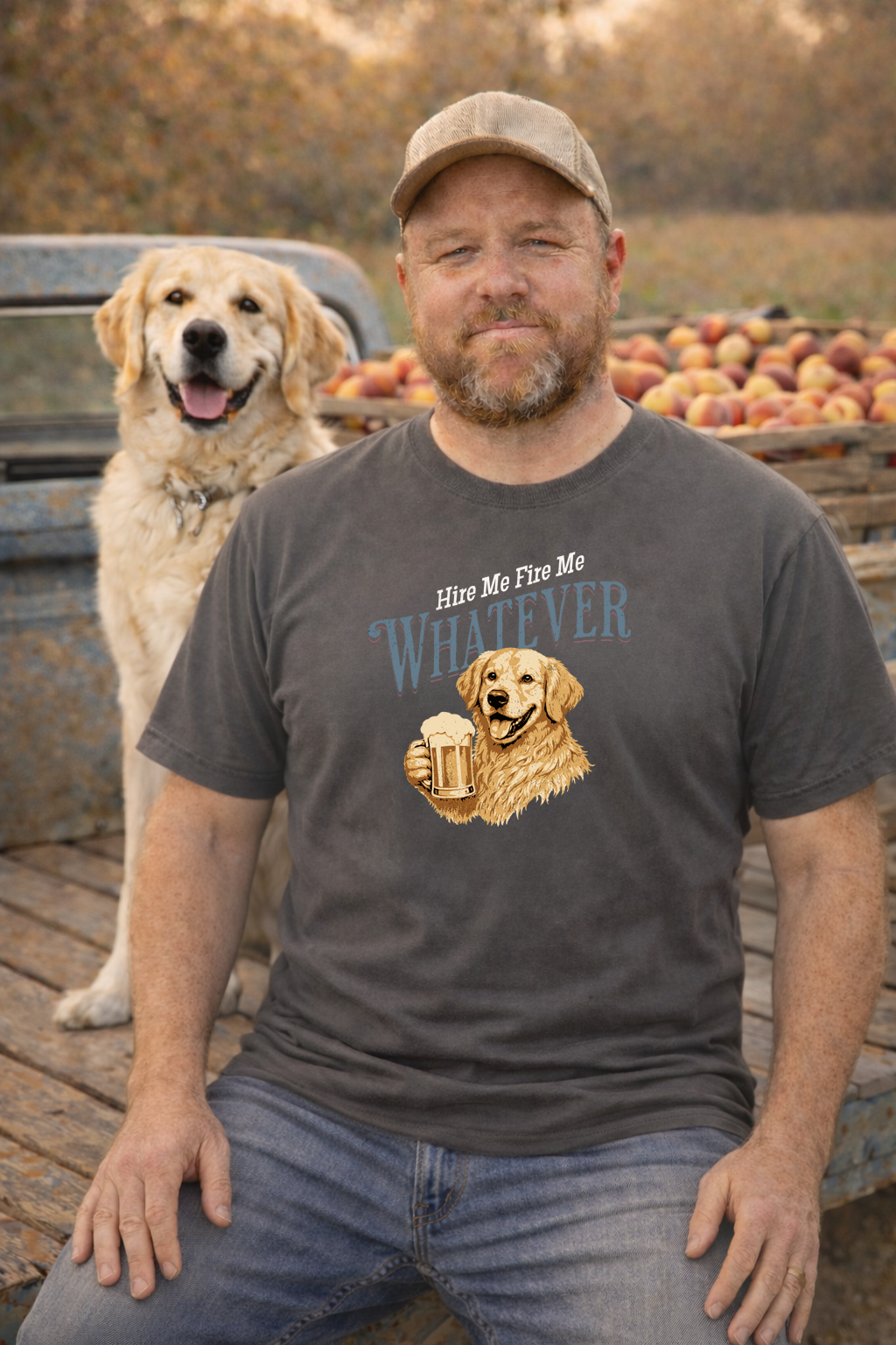 Man wearing a t-shirt with a dog graphic and text, sitting next to a dog in a field.