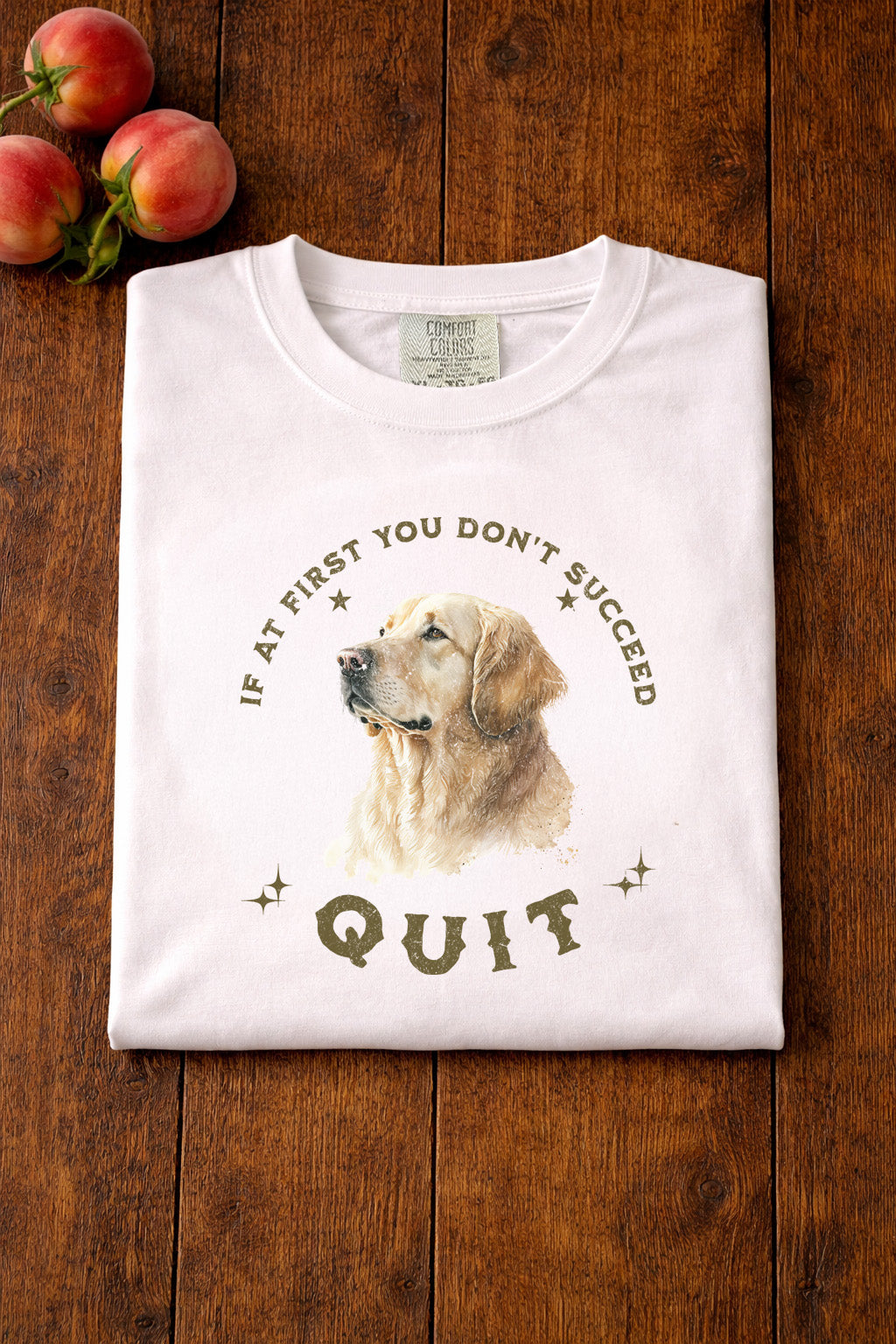 White t-shirt with a dog graphic and text on a wooden surface with peaches.