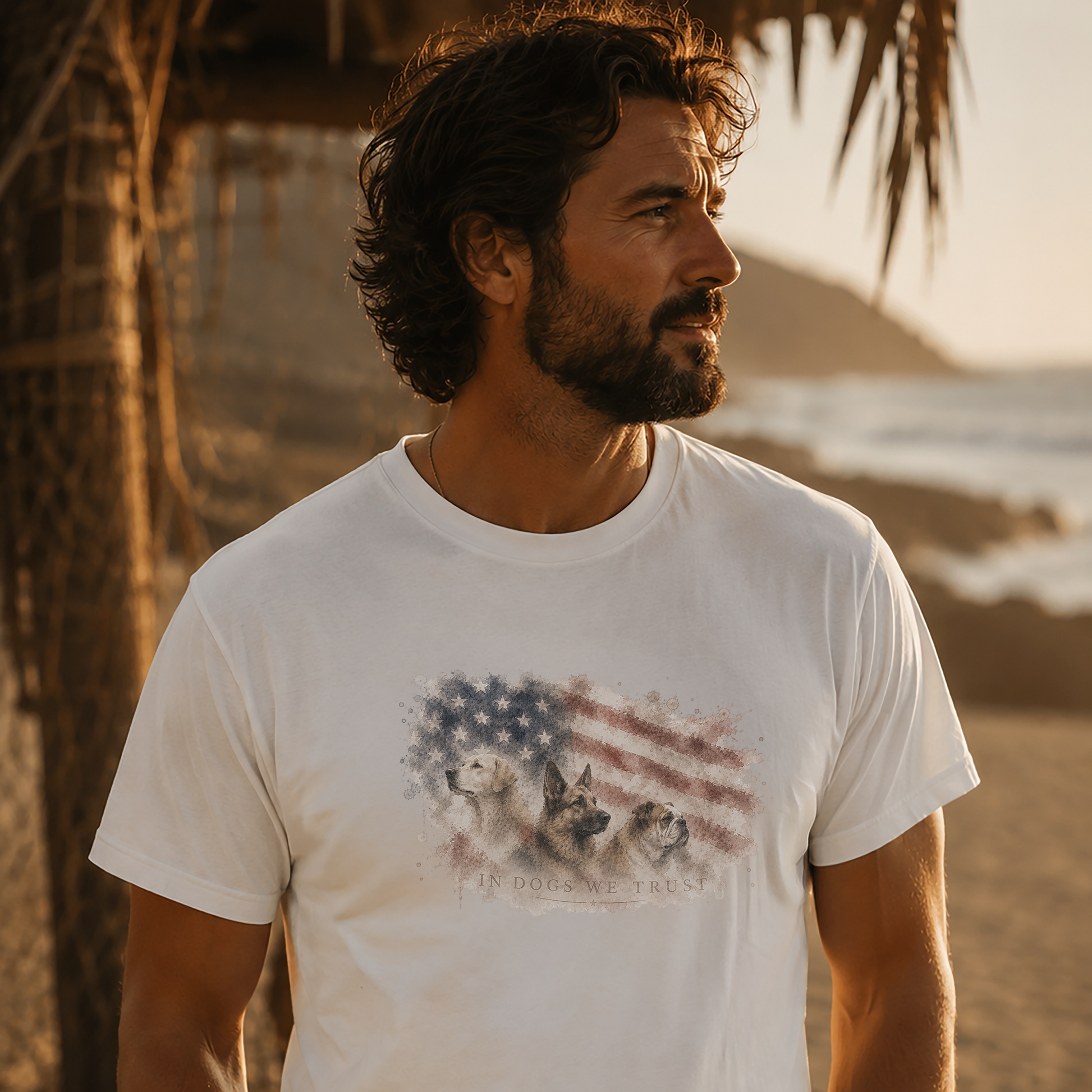 Man wearing a white t-shirt with a graphic design of dogs and an American flag on a beach.