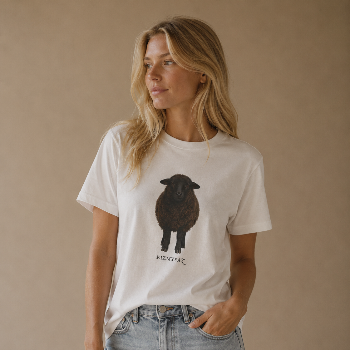 A woman wearing a white graphic t-shirt with a black sheep illustration and the text 'KERRY FC' underneath, paired with light-wash denim shorts, standing against a solid beige studio background.