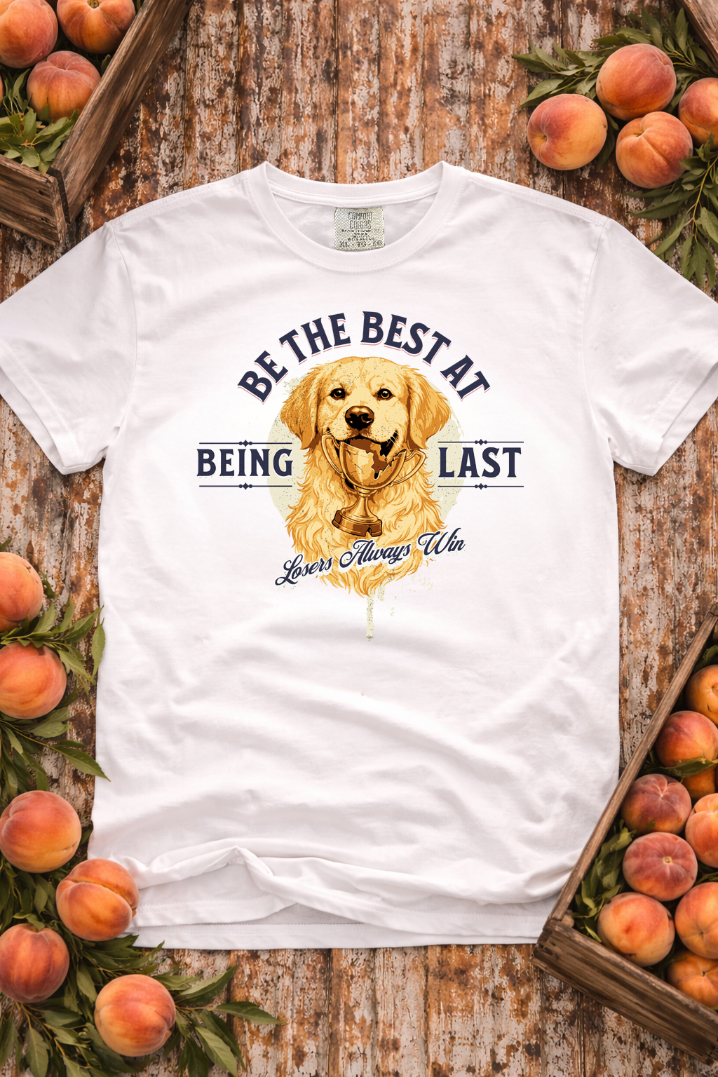 White t-shirt with a dog graphic and text on a wooden background with peaches.