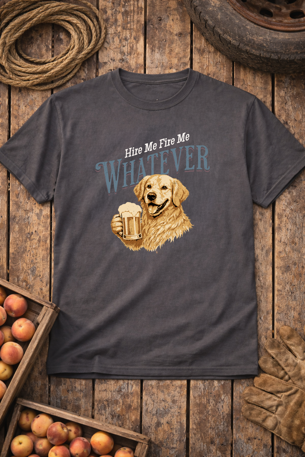 Gray t-shirt with a graphic of a dog holding a beer mug and text 'Hire Me Fire Me Whatever' on a wooden background.