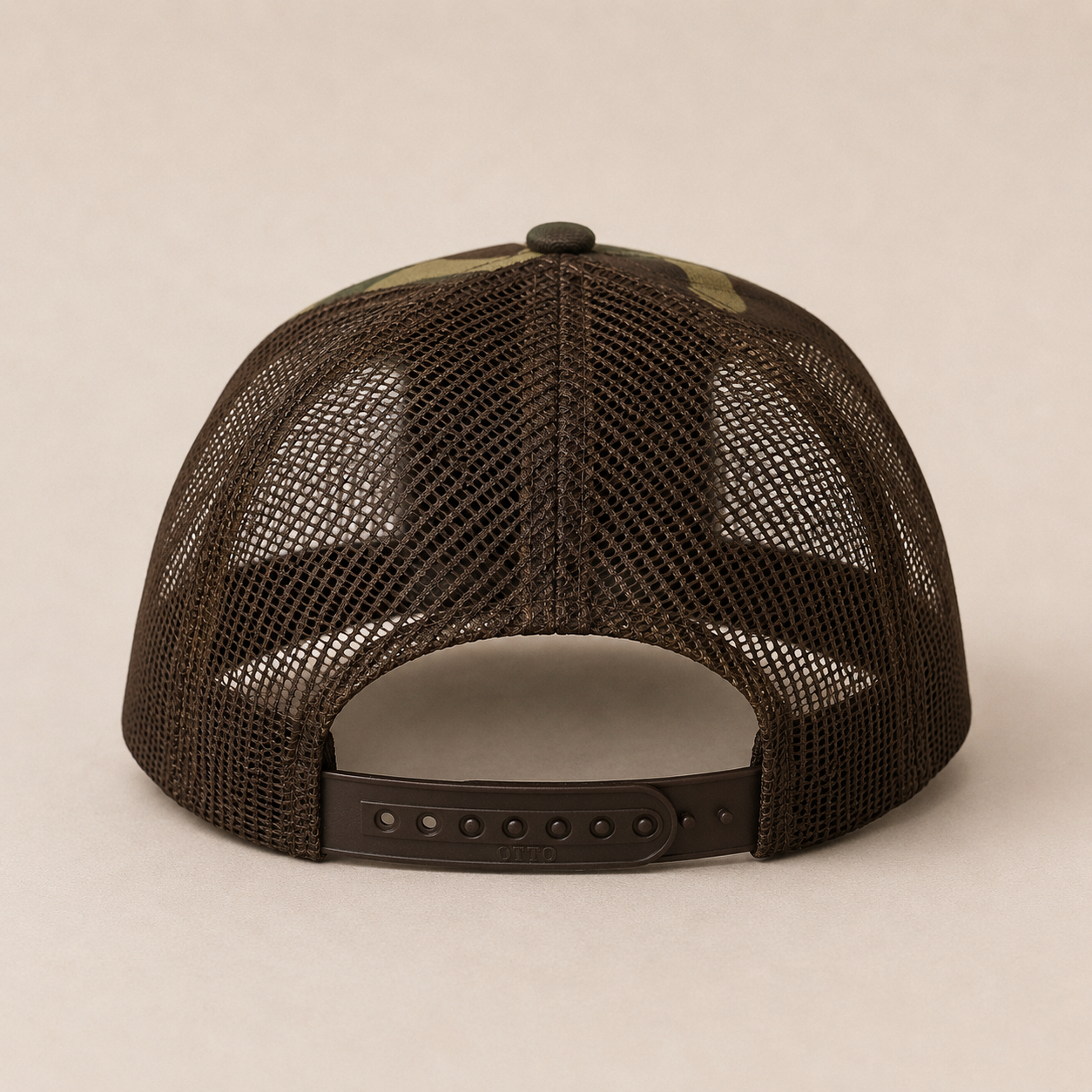 The back view of a dark brown trucker hat with a mesh back and an adjustable snapback closure, set against a plain beige background.